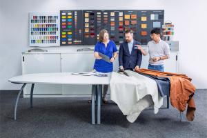 3 Experienced Bentley craftsmen working with varieties of Hides available, with sample board hung on wall.