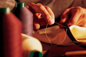 Close up of hands, sewing a Hotspur hide in Dream Factory, Crewe