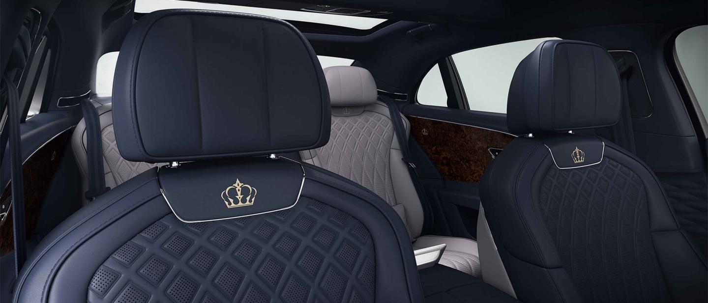 Front seats of Bentley Flying Spur Azure featuring lofted diamond-quilted seats in Damson hide with custom emblem. 