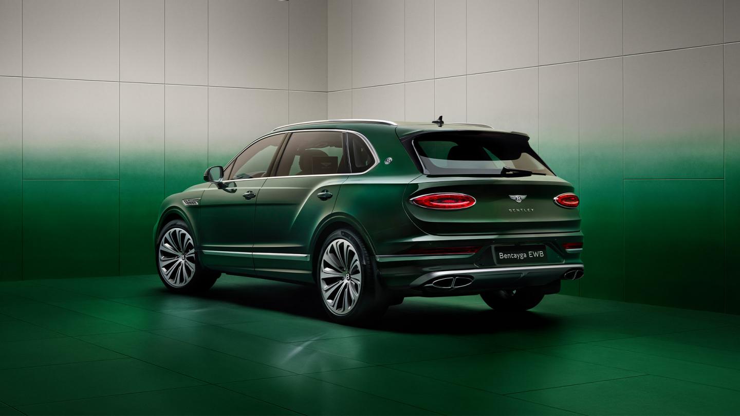 Wisdom Kaye standing next to the rear three quarter of the Bentayga Atelier Edition in an Emerald exterior colours with bright chrome accents
