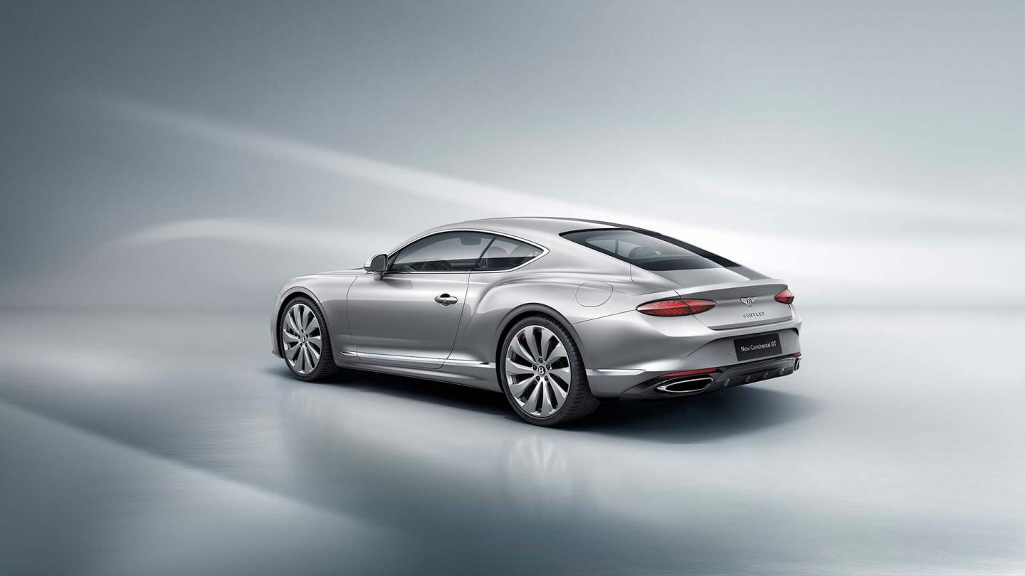 Rear three quarter of the new hybrid Bentley Continental GT in a Moonbeam exterior featuring 22" directional wheels