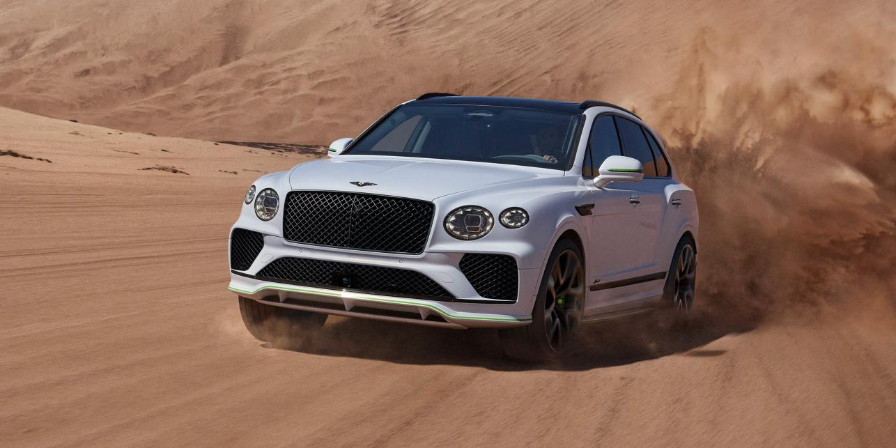 New Bentayga Speed in Snow Quartz by Mulliner exterior paint with the Bentayga Styling Specification and 23" Directional Wheels driving on sand dunes.