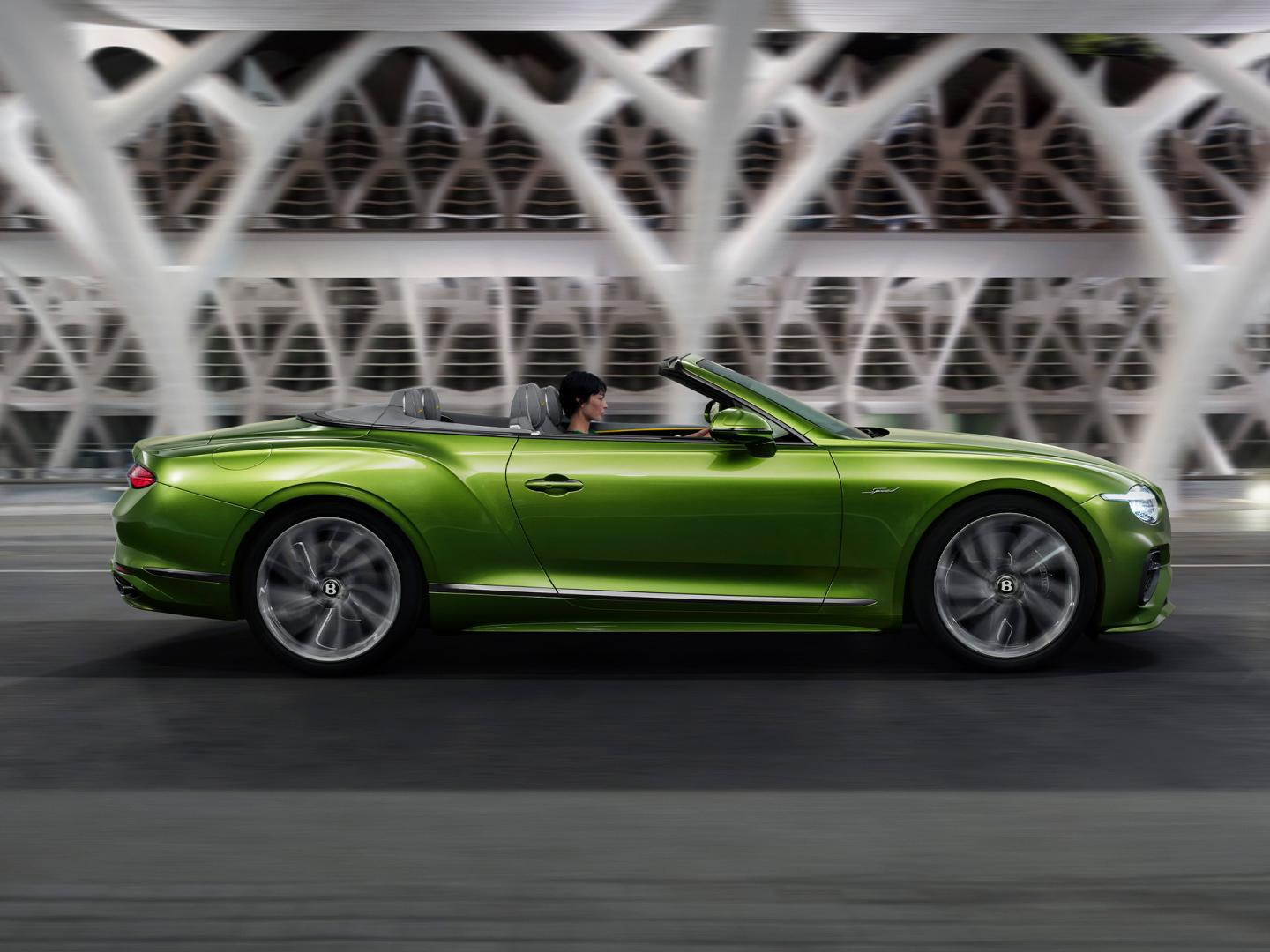 The new Hybrid Bentley Continental GTC Speed in Tourmaline Green driving in an urban environment