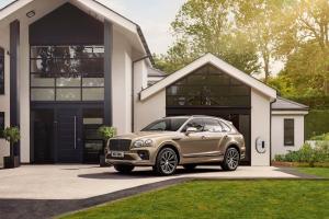 A Light Gazelle - by Mulliner coloured Bentley Bentayga Hybrid, side angled view featuring chrome matrix grille in black surround with Bentley branded EV charger in background.